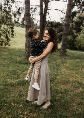 Gülümseyen çocuk ormanın derinliklerinde annesinin yüzünü nazikçe tutuyor..