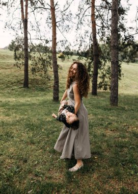 Annesi gülen oğlunu ağaçlarla çevrili bir parkta sallıyor..