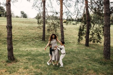 Anne ve oğulları ormanda neşeyle dans edip oynuyorlar..