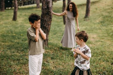 Anneleri yakınlarda saklanırken iki çocuk ormanda saklambaç oynuyor..