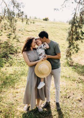 Parkta güneşli bir günde aile kucaklaşması.