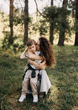 Anne ormanda oğlunu kucaklıyor ve öpüyor.