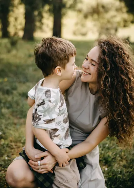 Gülümseyen anne, açık havada küçük oğluna sevgiyle bakıyor.