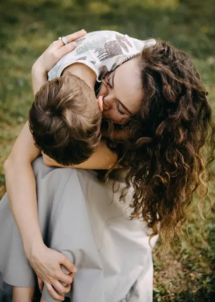 Bir annenin dışarıda çocuğunu kucaklayıp öptüğü şefkatli bir an.