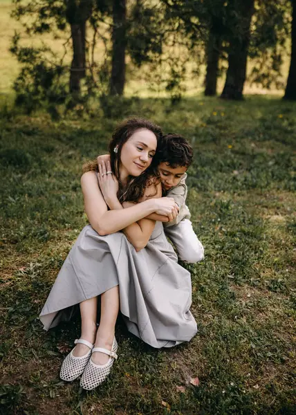 Bir anne ve oğlu arasında sevgi dolu bir an. Ormanda oturmuş, birbirlerine şefkatle sarılıyorlar..