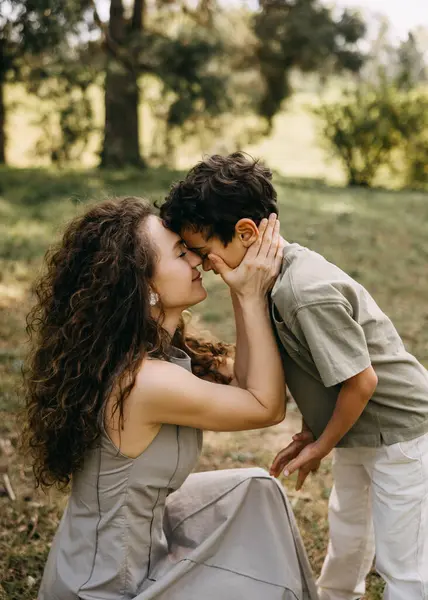 Bir orman parkında, alınlarını birbirine bastıran anne ve oğlunun yakın çekimleri. Duygusal aile bağlantısı.