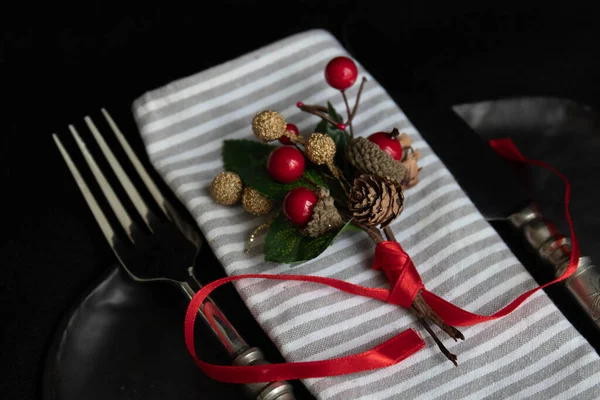 Grey Stripe napkin , red berries bouquet with red ribbon on black ceramic plate , vintage silver cutlery