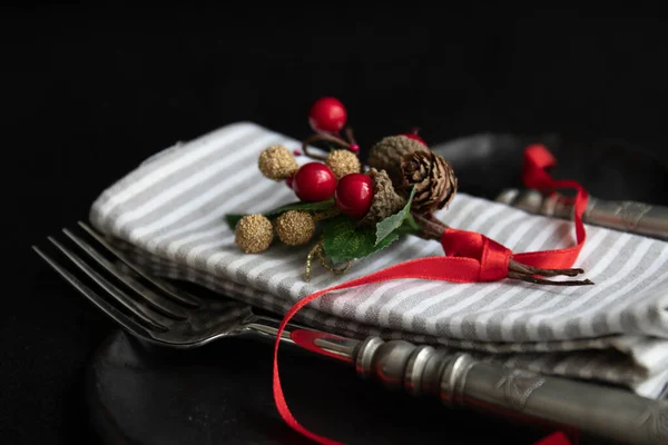 Grey Stripe napkin , red berries bouquet with red ribbon on black ceramic plate , vintage silver cutlery
