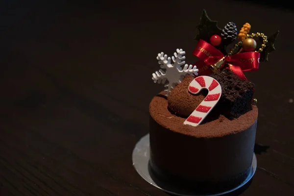 Tasty Chocolate Mousse cake decorated with Christmas candy cane, little white snow flake, a bouquet of berries
