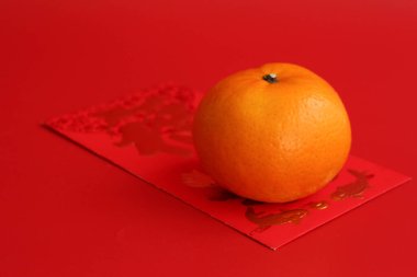 An Orange in a basket with the Lucky Red Envelope with the Script 