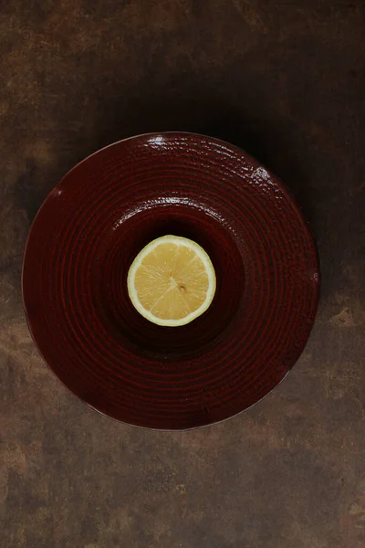 Close up single half lemon on a red plate, rustic background