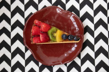 Beyaz arka planda lezzetli Danimarka meyveli keki, üstüne taze çilek, kivi, şeftali ve yaban mersini.