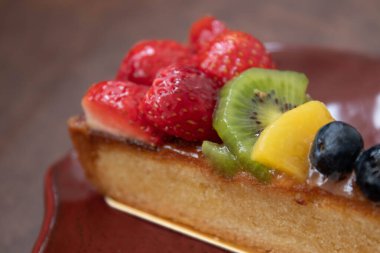 Beyaz arka planda lezzetli Danimarka meyveli keki, üstüne taze çilek, kivi, şeftali ve yaban mersini.