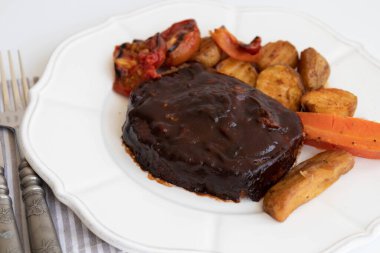 Izgara sebzeli domuz pirzolası, domates, havuç ve patates, beyaz arka planda.