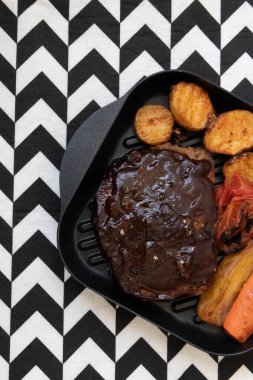 Izgara sebzeli domuz pirzolası, domates, havuç ve patates, beyaz arka planda.