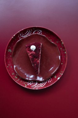 Kırmızı seramik tabakta kırmızı kadife kek, kırmızı arkaplan