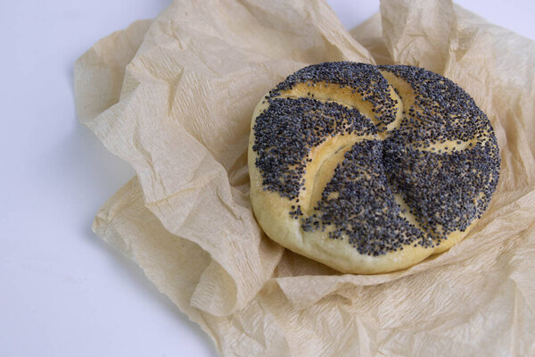 Poppy Seeds Kaiser Roll Wrapped with Brown Paper on White Background