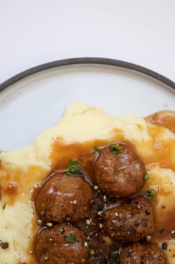 Evde hızlı yemek, köfte ve üzerine kahverengi sos konmuş patates püresi.