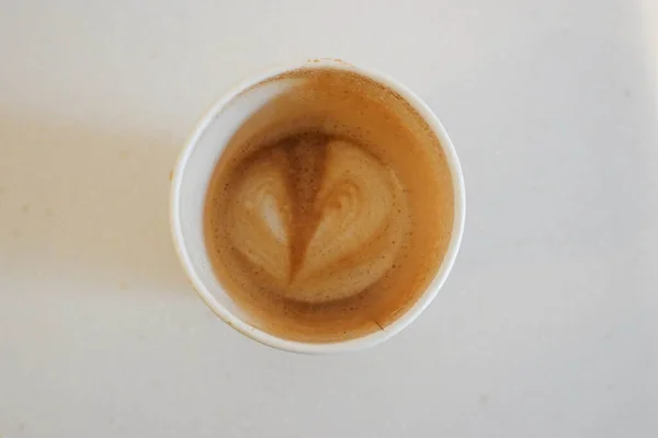 白い背景のコーヒーペーパーカップに泡の上に残されたハートの形 — ストック写真