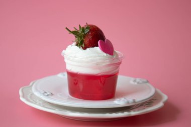 Üzerinde beyaz krema ve Pembe Kalp ve Pembe Arkaplan ile taze çilek olan çilek reçeli.