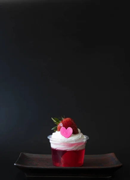 Strawberry jelly topped with white whip cream and Fresh Strawberry with Pink Heart, Black Background