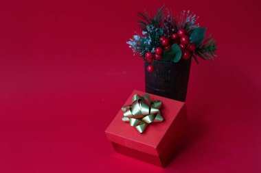 Kırmızı arka planda yeşil bardakta kırmızı böğürtlen desenli Noel süslemesi.