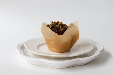 Beyaz arka planda beyaz bir tabakta çikolatalı fındıklı kek.