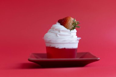 Kırmızı arka planda krem şantili lezzetli jöleli çilekli kek.