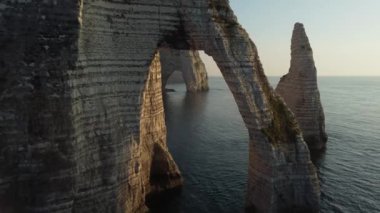 Güneş batarken Etretat 'ın nefes kesici güzelliğini keşfedin. Aşağıdaki ikonik tebeşir kayalıkları ve sakin sulara altın renkler dökün. Doğanın bu çarpıcı kıyı manzarasında sanatçılık parlıyor..