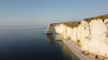 Etretat 'ın nefes kesici uçurumları sakin denizden görkemli bir şekilde yükselir, güneşin sıcacık parıltısıyla yıkanır. Dalgalar yavaşça kıyıya vurarak bu kıyı cennetinde huzurlu bir atmosfer yaratıyor..