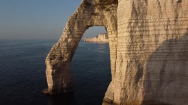 Güneş batmaya başladığında Etretat ikonik doğal kemerinin nefes kesici manzaralarını keşfedin, dingin sulara ve görkemli uçurumlara sıcak bir ışıltı saçın, doğanın inanılmaz sanatsallığını gösterin..