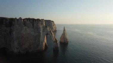 Güneş batarken Etretat ikonik uçurumlarının nefes kesen görkemine tanık olun. Dramatik kaya oluşumlarını ve sakin denizi aydınlatarak doğa severler için mükemmel bir atmosfer yaratıyor..