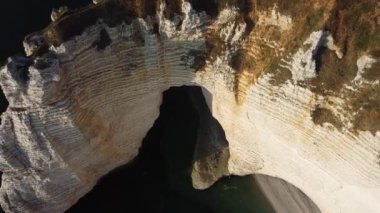 Güneş batmaya başladığında Etretat 'ın vurucu uçurumlarına dalgalar çarpar. Yükselen kireçtaşı oluşumlarına altın ışık saçar.