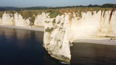 Etretat 'taki uçurumların nefes kesici güzelliğine tanık olun. Altın güneş ışığı, aşağıdaki sakin suları aydınlatan çarpıcı kireç taşı oluşumlarını okşuyor.