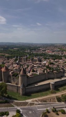 Carcassonne 'un nefes kesen manzarasına hayret ediyorum, çarpıcı duvarları ve tarihi kuleleri ile, yemyeşil manzaralar ve sıcak güneşin altında canlı kasaba hayatı ile iç içe..