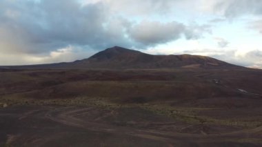 Lanzarote 'nin büyüleyici arazisini deneyimleyin. Günbatımının ılık parıltısı altında eşsiz volkanik oluşumlarını gösterin. Geniş gökyüzünde bulutlar dans ederken..