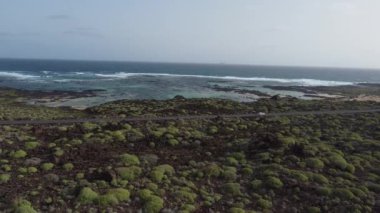 Güneş batarken, gökyüzünü canlı renklerle boyayan Lanzarote sahilinin nefes kesici güzelliğine tanık olun. Sakin dalgalar engebeli kıyı şeridine vurarak sakin bir atmosfer yaratıyor..