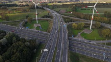 Yükselen rüzgar türbinlerinin ve hareketli bir otoyolun dingin bir arada yaşamasına tanık olun. Araçlar bu büyüleyici ortamda yemyeşil ve açık alanlarla çevrili olarak arazide geziniyor..