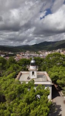 Deniz fenerinden Tossa de Mar 'ın nefes kesici manzarasını izleyin. Yeşillik ve dramatik bulutlarla çevrili bu manzaralı yer kıyı şeridinin eşsiz bir perspektifini sunuyor..