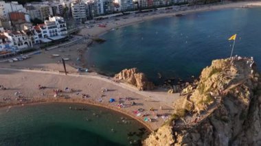 İnsanlar yaz sıcağının tadını çıkarırken, güneş sakin suların üzerinde batarken kumlu sahillerde uzanırken, hayat dolu manzarayı aydınlatırken, Blanes 'ın çarpıcı kıyı şeridini deneyimleyin..