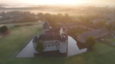 Güneş ışığının, Lavaux-Sainte-Anne Şatosu 'nu çevreleyen huzurlu sularda dans ederek büyüleyici mimarisini ve bereketli çevresini gözler önüne serdiği büyülü sabahı hissedin..