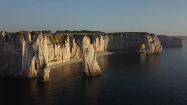 Altın güneş ışığının ikonik tebeşir kayalıkları ve sakin sulara sıcak bir parıltı saçmasıyla Etretat 'ın nefes kesici güzelliğini hissedin. Akşam karanlığında doğa sanatının en iyi hali..