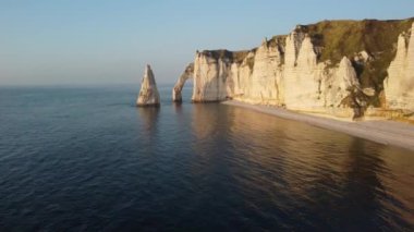 Dalgalar yavaşça Etretat 'ın görkemli tebeşir kayalıklarına çarpar güneş ufkun altına batarken, altın bir ışık saçar ve bu sahil taşının güzelliğini yükseltir, barışı ve yansımayı davet eder..