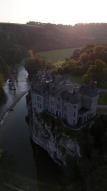 Güneş batarken bir uçuruma tünemiş Walzin Kalesi 'nin nefes kesen manzarasını ve aşağıdaki huzurlu nehrin üzerine ılık bir parıltı saçan görüntüsünü deneyimleyin..