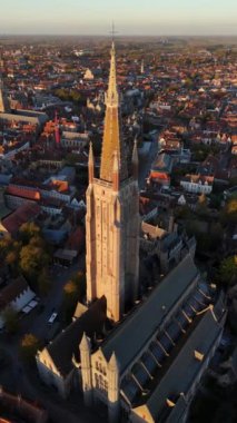 Güneş batarken Leydi Bruges Kilisesi 'nin nefes kesici güzelliğine tanık olun. Karmaşık mimarisi ve çevresindeki manzaraya altın ışık saçıyor. Büyüleyici bir manzara.