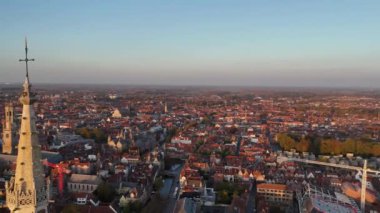 Büyüleyici manzaralar Bruges 'ün üzerinde sergileniyor, Meryem Ana Kilisesi' nin yanındaki çarpıcı mimariyi gözler önüne seriyor. Güneş ışığı çatılara ve tarihi binalara alacakaranlıkta ılık bir ışık saçıyor..