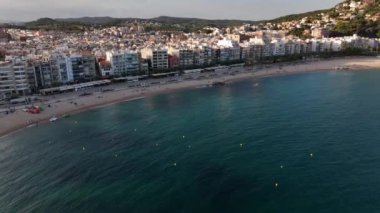 Alacakaranlıkta Blanes 'in dingin güzelliğini tecrübe et. Sahil şeridi altın kumlara karşı hafif dalgalarla parıldarken, canlı binalar sahili çevreleyerek çarpıcı bir sahil manzarası sergiliyor..