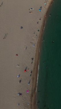 Kumsala gidenler güneşin altında dinlenirken, Blanes 'da kumlu kıyılara doğru sakin dalgalar süzülüyor. Renkli şemsiyeler manzarayı noktalıyor, keyif ve rahatlama için canlı bir atmosfer yaratıyor..