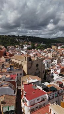Tossa de Mar 'ın nefes kesici manzarasını deneyin, çatıların yuvarlanan tepelerle buluştuğu. Bulutlu gökyüzü bu büyüleyici kıyı kasabası tarihi mimarisi için dramatik bir zemin oluşturur..