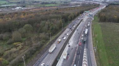 İnşaat trafiği yavaşlatırken, İngiltere 'de uzun araç kuyrukları yol çalışması boyunca ilerliyorlar. Verimli kırsal kesim, yollardaki hareketlilik için zıt bir zemin sağlıyor..